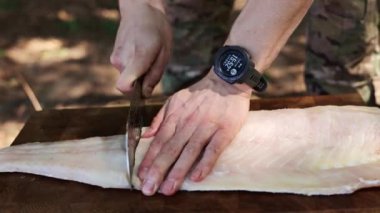 Ahşap bir tahtanın üzerinde taze bir balığı fileto yapıp keserken yakın plan çekimleri..