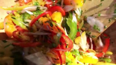 İki ahşap kaşık, salatayı rengarenk taze biberlerle ahşap bir kaseye atar.