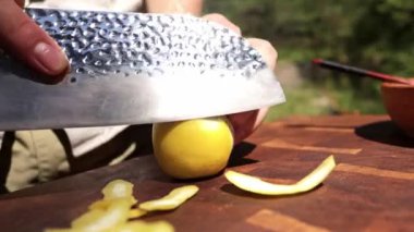 Şefin ellerini yakın, dışarıdaki ahşap kesme tahtasındaki limonun kabuğunu kesiyor.