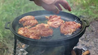 Kamp ateşinde pişen ve cızırdayan tavuk butlarını yakın..