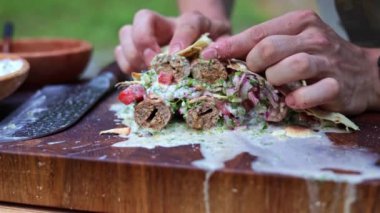 Yumuşak kofta kebabını taze sebzelerle ve kremalı sosla kaplayıp ağız sulandıran bir yemek hazırlarken yakın plan çekimler..