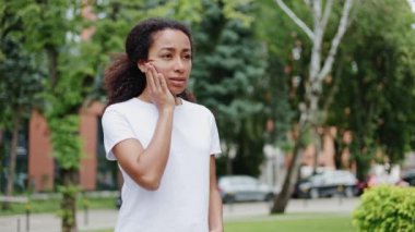 Hüsrana uğramış Afro-Amerikan kadın portresi. Ağızda keskin bir ağrı hissediyor ve dişçinin yardımına ihtiyacı var. Sıradan beyaz tişört giymiş, yanaklarına dokunan ve ağrıdan muzdarip üzgün bir kadın..