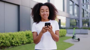 Çekici bir kadın, gür saç stili, uzak bir erkek arkadaşla mesajlaşan, neşeli bir yüz ifadesi olan. Uygulamada cevap ararken gözlerini kaçıran romantik bir kadın..