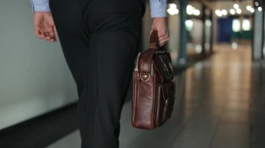 Çantası olan bir iş adamı boş bir ofis koridorunda yürüyor..