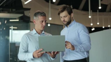 Ofis ortamında dizüstü bilgisayara bakarken tartışan iki erkek iş adamı..