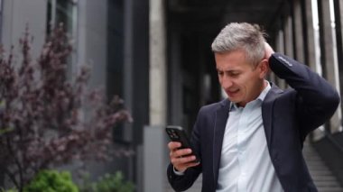 Endişeli iş adamı toplantısına giderken telefonundan üzücü haberler alıyor. Takım elbise ve kravat takmış ve çok mutsuz görünüyor..