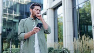 Stresli iş adamı telefonunda kötü haberler okurken göğsünde ağrı ve nefes darlığı çekiyor. Şehir geçmişi. Sağlık sorunları kavramı.