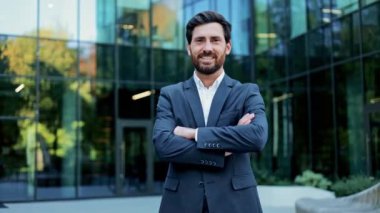 Mutlu, kendinden emin bir iş adamı bir şirket binasının önünde duruyor. Kollarını kavuşturup kameraya gülümsüyor, başarıyı, hırsı ve liderliği resmediyor. Bu video bazı duyguları çağrıştırıyor.