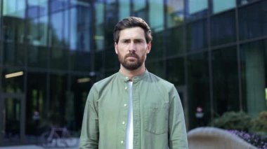 Modern bir ofis binasının önünde duran genç bir işadamı kollarıyla dur işareti yapıyor ve olumsuz tepki veriyor..