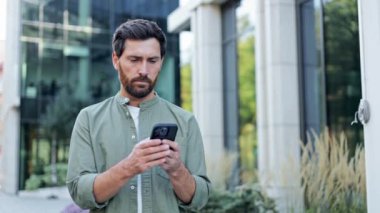 Genç bir iş adamı telefonundaki bir şeye bakarken strese girer. Bir ofis binasının önünde duruyor..