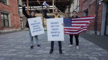 Üç Amerikalı protestocu ve otomasyon karşıtı protesto sırasında Amerikan bayrağı taşıyor. İşlerini ve haklarını savunmak için dayanışma içinde duruyorlar..