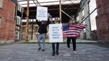 ABD 'deki liman işçileri otomasyon ve robotlar nedeniyle işten çıkarmaları protesto ediyorlar. İşlerini ve haklarını gösteren bir Amerikan bayrağı taşıyorlar..