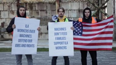 Liman işçileri otomasyon, iş kaybı, tabela ve Amerikan bayrağını protesto ediyorlar. İşçi hakları ve iş güvenliğini savunuyorlar..