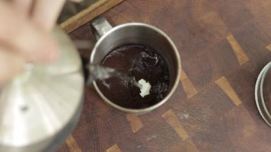 Birisi bir fincan kahve telvesine sıcak su döker. Kahve göl kenarındaki bir kamp ortamında hazırlandı. Balkabağı kızartıldı ve dışarıda servis edildi. Sonbahar için mükemmel..