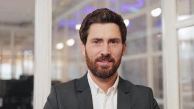 Ofis ortamında gülümseyen bir iş adamının portresi. Girişimciliği ve liderliği temsil ederek güven ve başarı yayıyor..