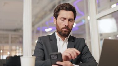 Bir işadamı ofisinde oturuyor, cep telefonu ve dizüstü bilgisayarını kullanarak bazı işleri hallediyor. İşine odaklanmış ve kendini işine adamış biri..