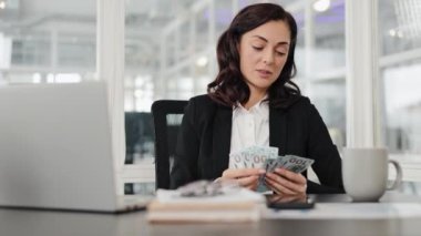 İş kadını ofiste Amerikan dolarlarını sayıyor. Mutlu görünüyor ve yakınındaki biriyle konuşuyor..