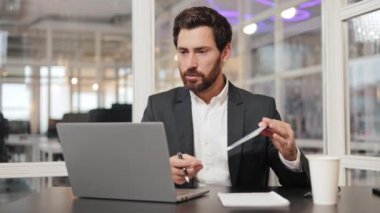 Takım elbiseli bir işadamı ofisinde masasında oturuyor ve bir video konferans görüşmesinde şirket verilerinin grafiklerini gözden geçiriyor. Çevrimiçi internet araması sırasında kağıt üzerinde finansal tabloları açıklayan genç bir işçi.