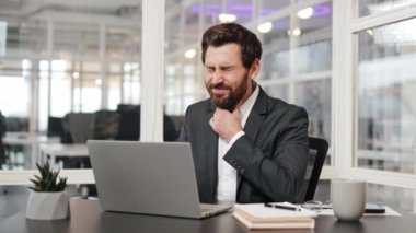 Hasta iş adamının boğazı ağrıyor, öksürüyor ve laptopla çalışıyor. Takım elbiseli stresli adam soğuk algınlığından ya da ofisin içinde çalışırken grip olmuş. Üzgün işçi virüs kapmış, işyerinde hastalık var..