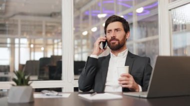İş yerinde cep telefonuyla konuşan mutlu bir girişimci ile meşgul. Genç profesyonel cep telefonuyla arıyor ve elinde fincanla boş vakit geçiriyor. Kendine güveni olan bir çalışan, kapalı alanda çoklu görev yapıyor..