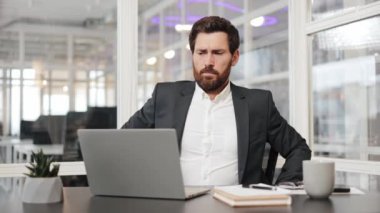 Bir iş adamı acı içinde masasında oturuyor. Sırt ağrısı çekiyor. Dizüstü bilgisayarıyla çalışıyor. Sırtını yaslamak için işe ara veriyor..