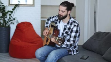 Evde akustik gitar çalan yakışıklı bir müzisyen. Salonda şarkı besteleyen yetenekli bir serbest yazar..