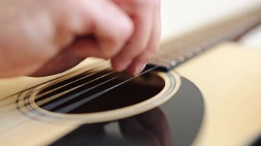 Profesyonel müzisyen evde akustik gitar çalar. Gitarist telleri ayarlar ve çalmaya hazırlanır..