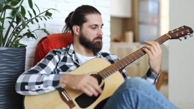 Evinde akustik gitar çalan yakışıklı bir müzisyen. Yetenekli adam modern dairede bir şarkı besteler..