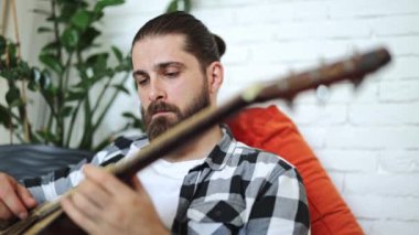 Evde akustik gitar çalan yetenekli bir müzisyen. Profesyonel serbest sanatçı dairede müzik yapıyor..