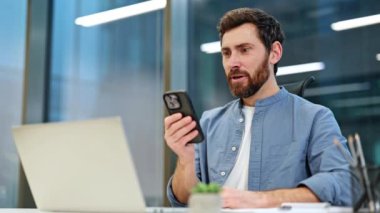 Heyecanlı iş adamı modern ofiste telefonla iyi haberler alıyor. Mutlu profesyoneller başarıyı, başarıyı kutlar. Öforik adam mesajı okuyor ve anlaşmayı kazanıyor..