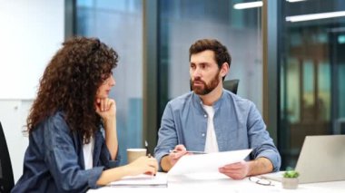 Odaklanmış meslektaşlar modern bir ofiste bir projeyi tartışıyorlar. İş adamı ve iş kadını bir anlaşma üzerinde birlikte çalışıyorlar. Profesyonel işbirliği ve takım çalışması.