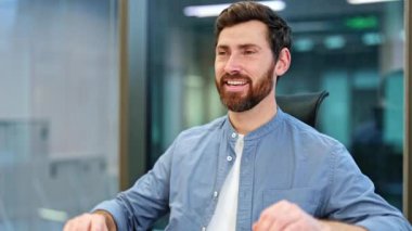 Başarılı iş adamı dizüstü bilgisayarı kapatıyor, arkasına yaslanıyor ve modern ofisteki başarısının tadını çıkarıyor. İşinden memnun..