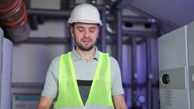 Kazan dairesinde kendine güvenen sakallı bir adam. Kasketli ve üniformalı sanayi tesisatçısı. Isıtma sistemi ekipman denetimi. Mühendislik, bakım işi.