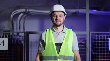 Kendinden emin elektrik mühendisi kollarını elektrik santralinin önünde kavuşturarak duruyor. Elektrik kontrol paneli, mühendislik ve elektrik dağıtım konsepti.