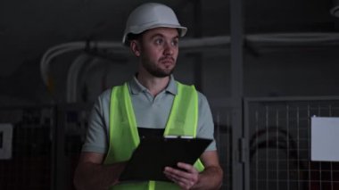 Ciddi elektrik mühendisi, elektrik kontrol panelinden ölçümler alıyor. Karanlık bir odada çalışan endüstriyel elektrikçi. Profesyonel işçi sunucu odasındaki elektrik santralini inceliyor..