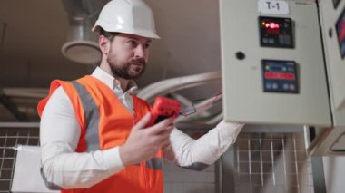 Kafkasyalı elektrik mühendisi, elektrikli ekipman kontrolü yapıyor. Çoklu sayacı olan endüstriyel elektrikçi elektrik santralini kontrol ediyor. Elektrik odasındaki profesyonel elektrikçi..