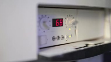 Kazan ısısını ayarlayan profesyonel bir tesisatçıya yakın çekim. Isıtma sistemi ekipmanlı kazan dairesi. Tesisatçı sıcaklığı 20 dereceye yükseltiyor..