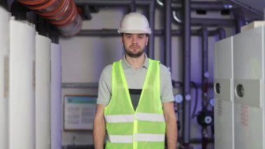 Ciddi Endüstriyel Mühendis Kolları Kazan dairesinde çapraz pozlar veriyor. Sağlam şapkalı, kendine güvenen teknisyen fabrikada güvenle duruyor..