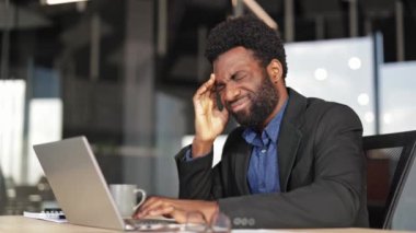 Modern bir ofiste dizüstü bilgisayarı üzerinde çalışırken başı ağrıyan hayal kırıklığına uğramış genç bir işadamı. Şakaklarını rahatsızlıkla ovuyor, iş stresiyle boğuşuyor..