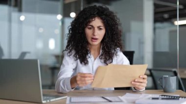 Ofis masasındaki bir mektupta kötü haber okuyan hayal kırıklığına uğramış bir iş kadını. Tek eliyle kafasını tutuyor, şok olmuş ve kafası karışmış bir şekilde..