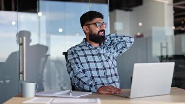 Sakallı Hintli işadamı modern ofiste masa başı iş yapıyor. Yorgun erkek girişimci işe ara verir. Stres, aşırı çalışma, işyeri sağlık konsepti.