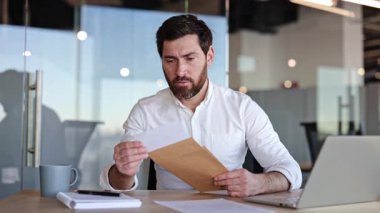 Hüsrana uğramış iş adamı bir mektupta kötü haberler okuyor. Sinirli erkek girişimci işten atılma ilanı alıyor. Modern ofis içi.