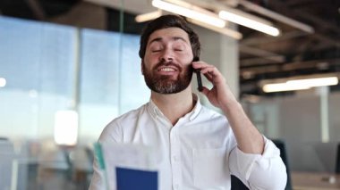 Sakallı iş adamı telefonda konuşuyor. Neşeli erkek menajer elinde biletlerle bir pasaport tutuyor, akıllı telefondan müşteriyle konuşuyor. Başarılı girişimci ofiste hoş sohbetler yapıyor..