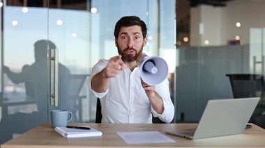 Hevesli, sakallı bir işadamı ofisinde oturmuş megafonla tutkuyla konuşuyor. Kararlılık ve inançla el kol geziyor..