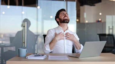 Boyun ve omuz ağrısından muzdarip hayal kırıklığına uğramış bir iş adamı. Yorgun bir adam modern bir ofiste masasında otururken boynuna ve omuzlarına masaj yapıyor..