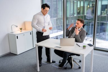 Confident professionals collaborating in a modern office. Dressed formally, discussing corporate strategies. Bright, contemporary workspace creates a productive atmosphere for teamwork communication. clipart