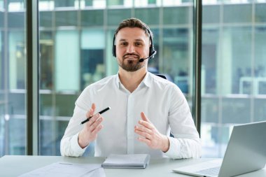 Kulaklık takan profesyonel danışman modern bir ofiste online bir toplantı düzenliyor. Profesyonel iletişim sırasında netlik ve bağlılık gösteriyor. Uzaktan kumandalı şirket için ideal.