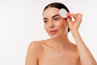 Cilt bakımı için pamuk pedi kullanan bir kadının portresi temiz bir minimalist geçmişe sahip temizleyici güzellik ve sağlıklı cilt bakımını gösteriyor. Güzellik ve hijyen kavramları için mükemmel..