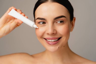 Cilt kremi süren parlak ve neşeli bir birey güzelliği, sağlığı ve kendine bakımı vurguluyor. Görüntü pozitiflik yayıyor ve canlı yaşam ve sağlığa yeni bir yüz yaklaşımı sergiliyor..