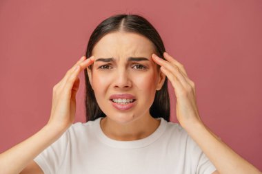 Stresli ve rahatsız edici bir ifadeyle başını tutarak insan duygularını ve tepkilerini gösteren bir kadın..